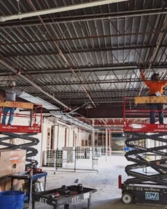 Electricians working on elevated platforms inside a large building in Plattsburgh, NY