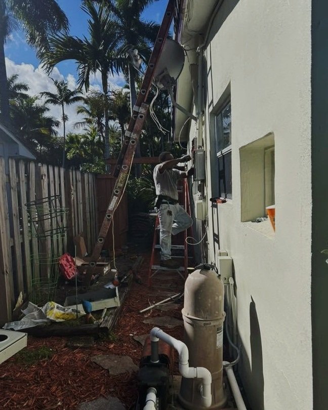 Electrician on a ladder doing exterior wiring in Plattsburgh, NY