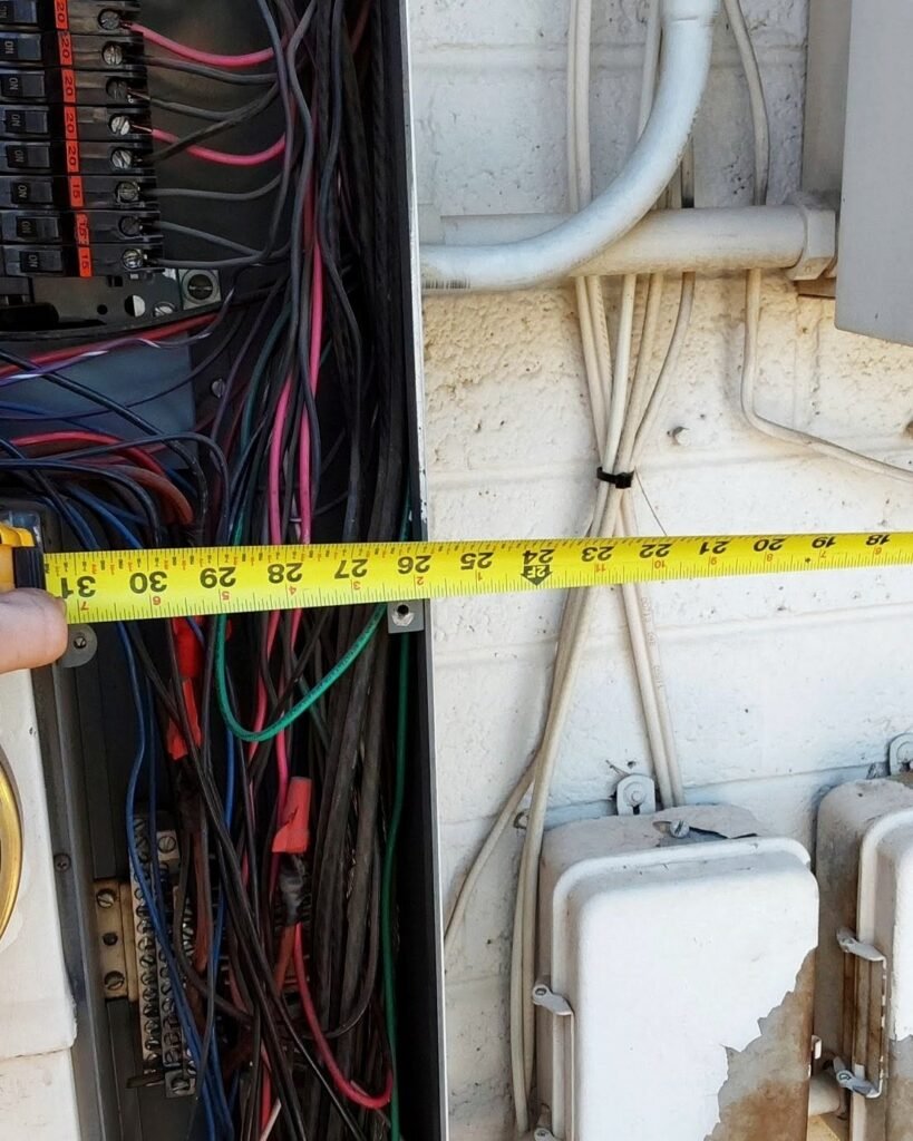 Electrician checking panel wiring with a tape measure in Plattsburgh, NY